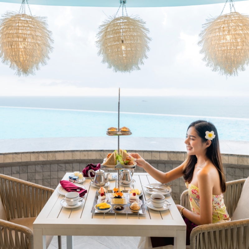 woman enjoying afternoon tea by the sea at a cafe in pattaya